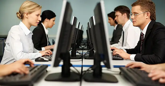 Four person customer service team working at desktop computers